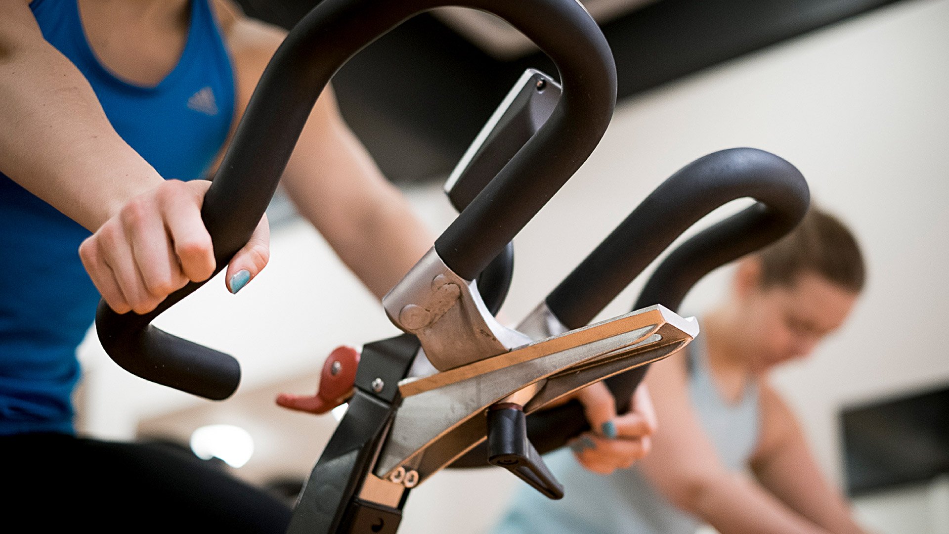 Kaksi naista polkee kuntopyörää spinning-tunnilla.